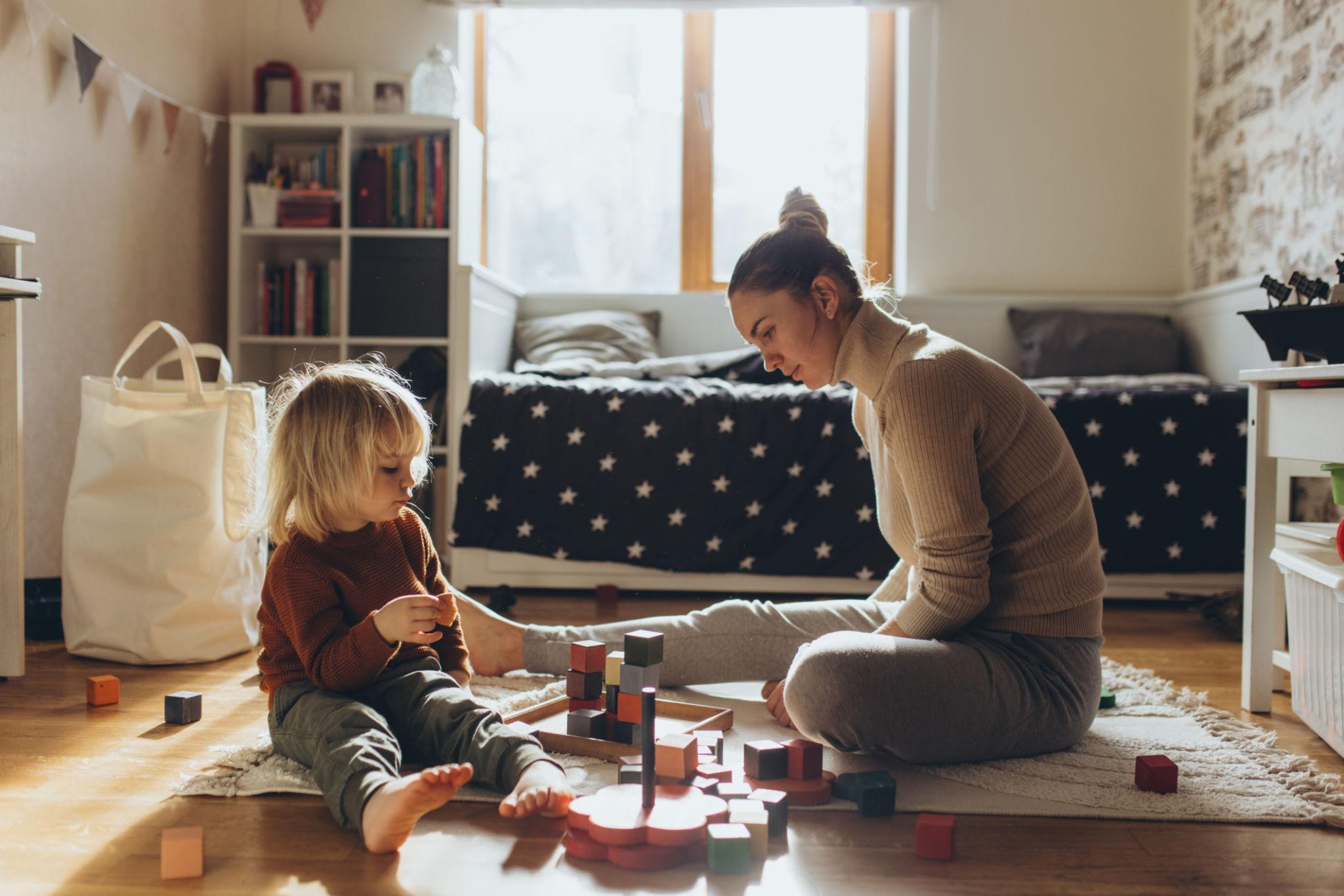 Mãe e filho brincando com blocos de madeira no chão